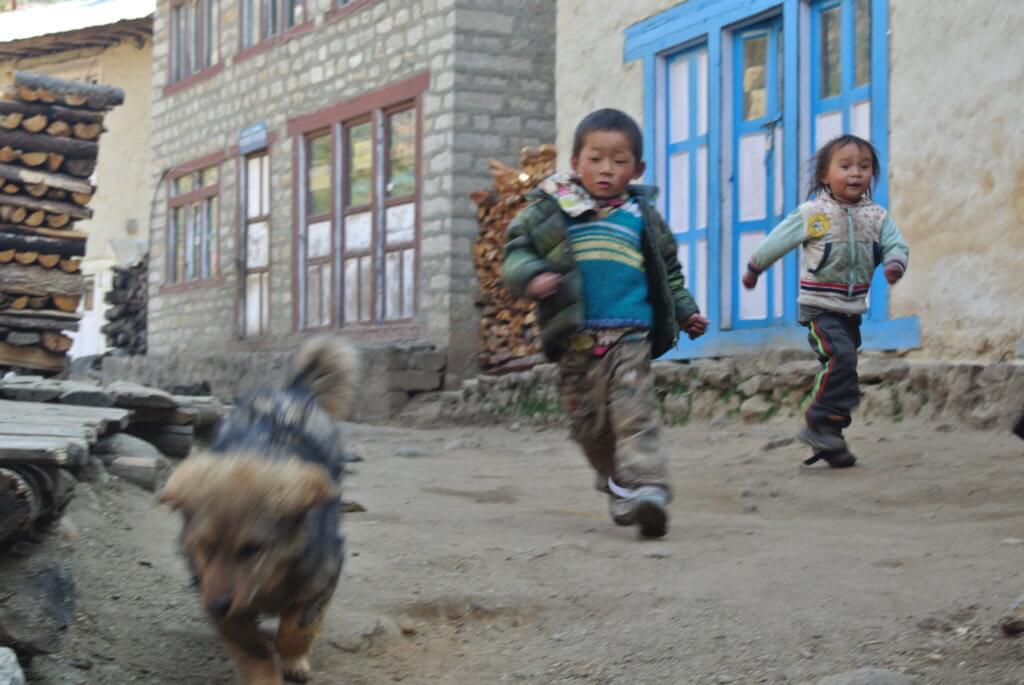 Two children running from their home, family dog leading the way, to see what treats the trekking stranger has brought to share on the trail.