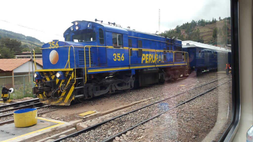 Blue train with yellow lettering, "PERURAIL" departing the Poroy Station en route to Aguas Calientes and Machu Picchu!